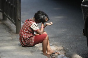 A girl sits on a pavement waiting to receive alms at a street in Mumbai 