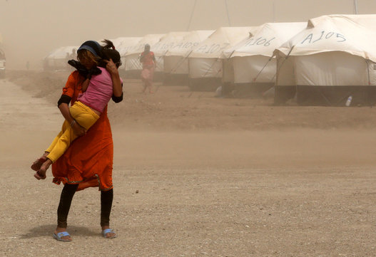 An internally displaced Iraqi woman holds her sister during a sandstorm outside the Bajid Kandala camp in Feeshkhabour, Iraq on Aug. 19, 2014. (AP Photo/Khalid Mohammed)