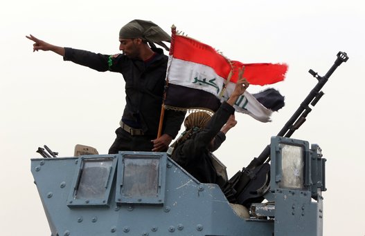 Members of Iraqi anti-terrorism forces wave the national flag in celebration after securing a checkpoint from Sunni militants in the village of Badriyah, west of Mosul, Iraq on Aug. 19, 2014. (AHMAD AL-RUBAYE/AFP/Getty Images)