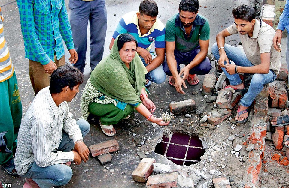 A woman displays a mortar shell fired by Pakistani troops that damaged the roof of her house at Arnia in Jammu.