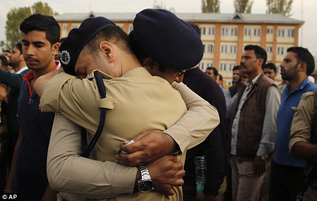 Indian police officers try to comfort each other as they cry during the wreath laying ceremony