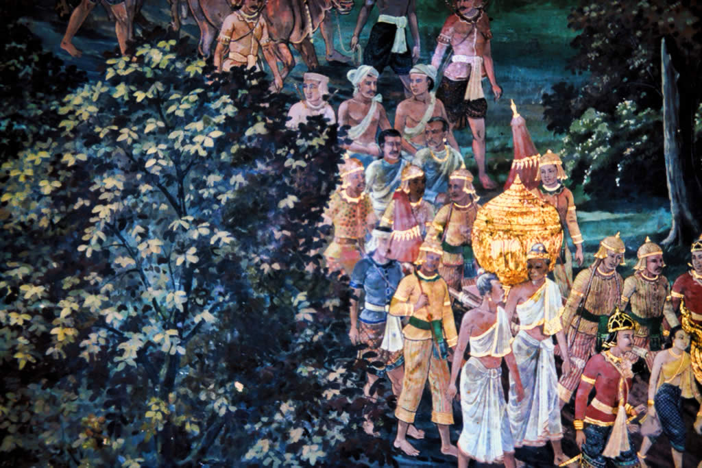 In this scene detail from a painted mural at the Emerald Buddha Temple, Bangkok, Thailand, baby Sita’s golden urn is carried to the king’s palace in a royal procession. The beautifully dressed king’s courtiers, carrying the closed golden urn, pass from the back to the front of the right half of the image. 